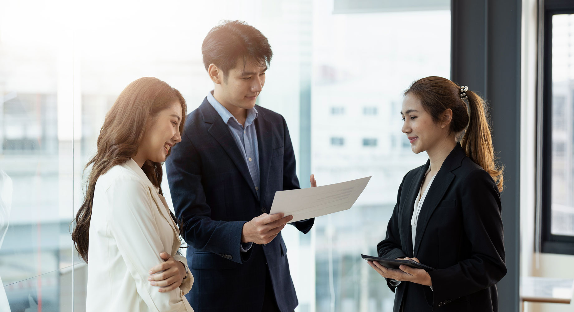 Three professionals collaborating in modern office, discussing documents and strategies for leasing & retail opportunities