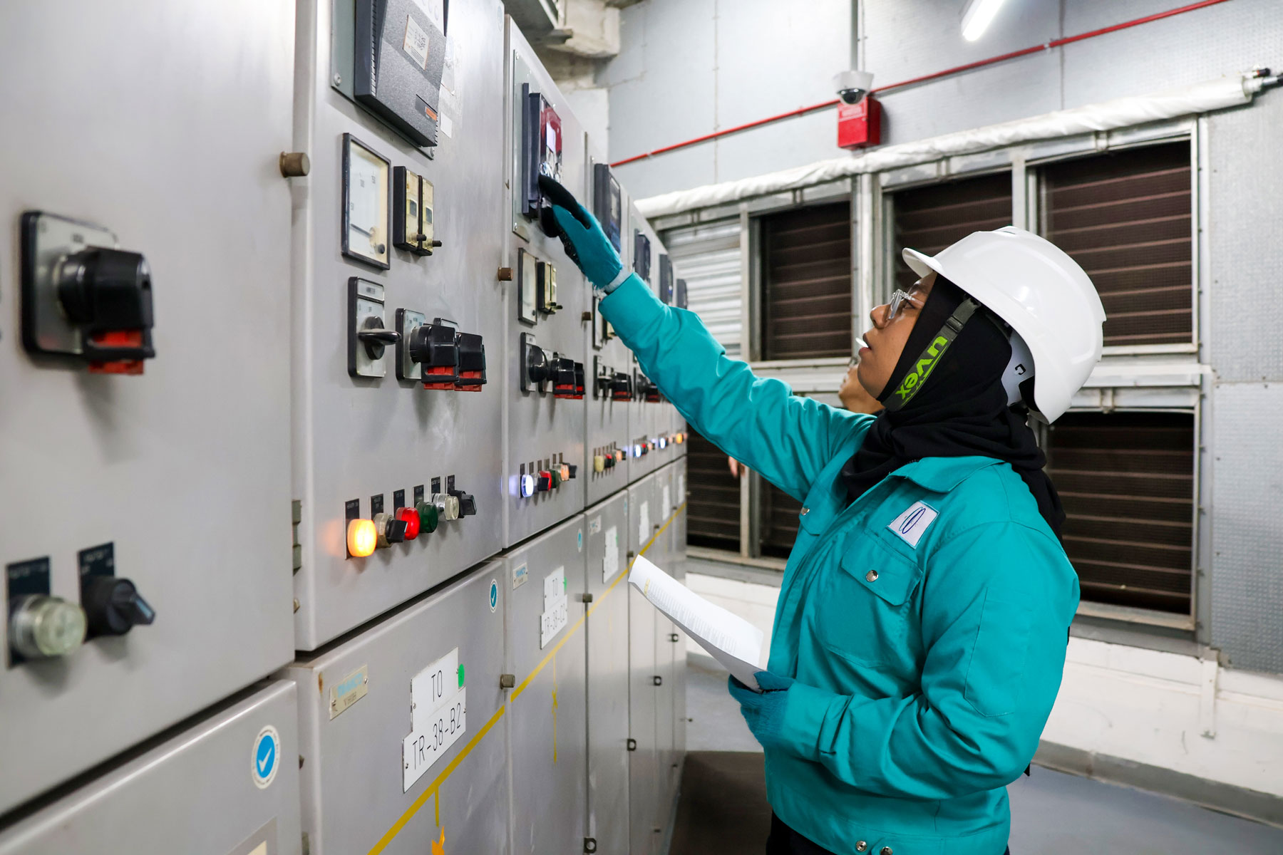 Engineer inspecting electrical panel in industrial control room, demonstrating technical expertise and facility management services